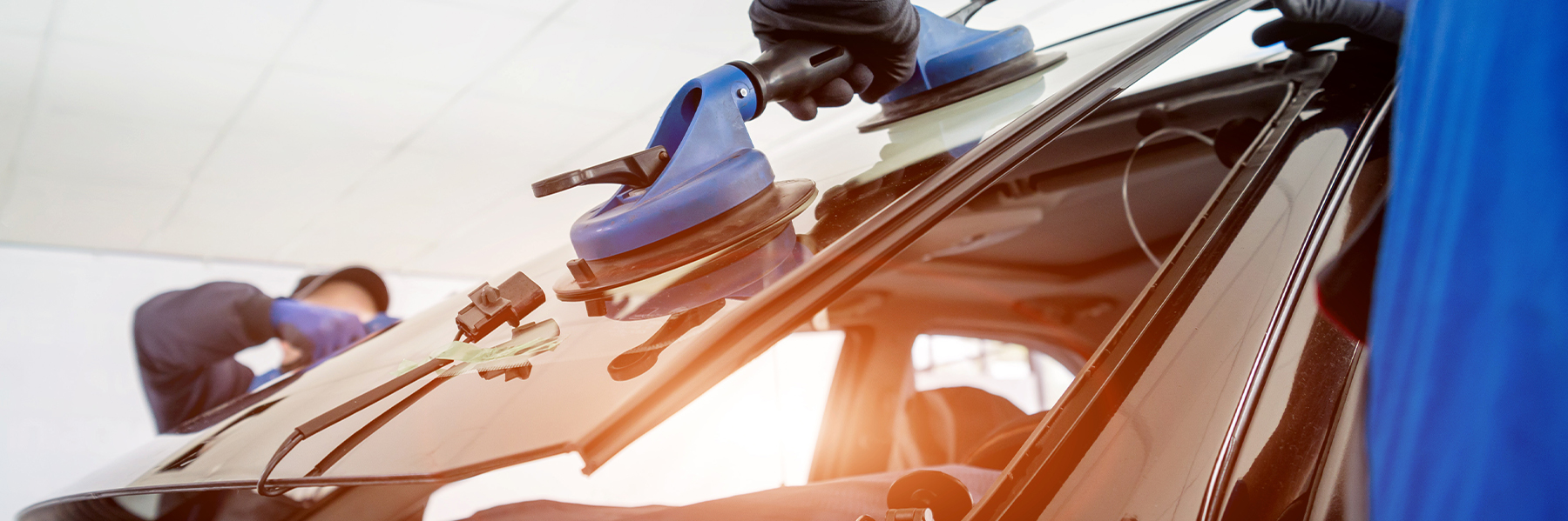 Autoglaser ersetzen Windschutzscheibe eines Autos in der Autowerkstatt.