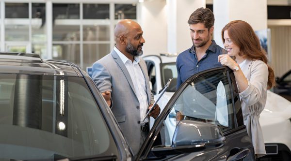 Garantiesachbearbeiter mit Kunden in der Beratung an einem Fahrzeug mit offener Fahrertür