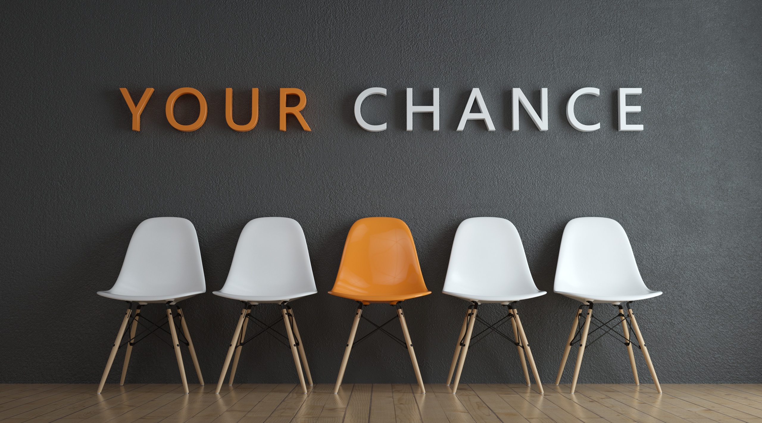 Der Schriftzug "Deine Chance" steht über vier weißen und einem orangefarbenen Stuhl. Es befindet sich in einem Wartezimmer vor einem Vorstellungsgespräch.